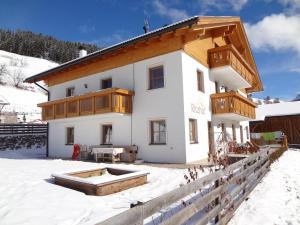 ein Haus im Schnee mit einem Holzdach in der Unterkunft Ritzhof in Villnöss