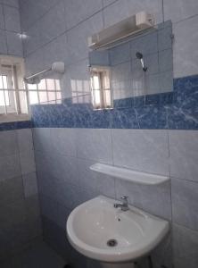 Un baño blanco con lavabo y espejo. en LUXURY, en Cotonou