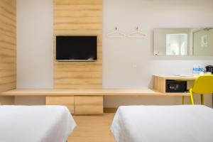ein Schlafzimmer mit zwei Betten und einem Fernseher an der Wand in der Unterkunft Summer View Hotel in Singapur