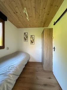 a bed in a room with a wooden ceiling at Bungalow de Zwaluw in Biddinghuizen