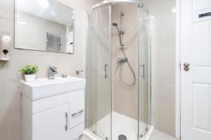 een witte badkamer met douche en wastafel bij 3 BDR House near East Croydon Rail Station in Croydon