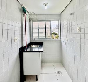 a white tiled bathroom with a sink and a window at João Machado Fortes in Florianópolis