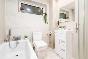 een witte badkamer met een toilet en een wastafel bij 3 BDR House near East Croydon Rail Station in Croydon +62 foto's