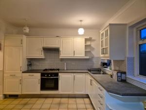 a kitchen with white cabinets and a stove top oven at Baraka Altmore in London