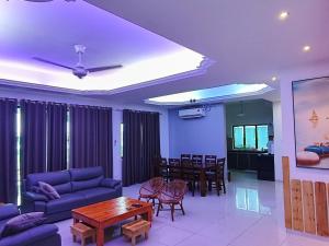 ein Wohnzimmer mit einem blauen Sofa und einem Tisch in der Unterkunft Pangkor L30 88 Corner villa House in Pulau Pangkor