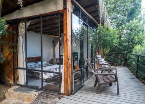 a porch of a house with a bed and chairs at Cabañas de montaña en Chía - Satorinatural in Chía