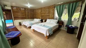 a hotel room with two beds and a table at Colibrí in Sarapiquí