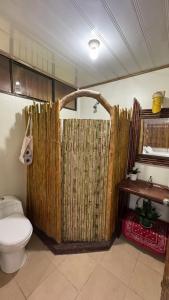 a bathroom with a toilet and a bamboo shower curtain at Colibrí in Sarapiquí
