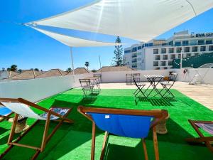 a patio with chairs and tables and a green floor at ALGARVE HOSTEL by Sweet Spot for us in Faro