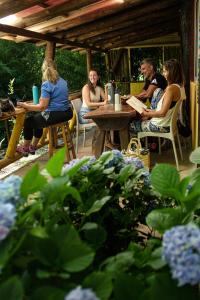un grupo de personas sentadas en una mesa en un jardín en HOSTEL CASA C Alojamiento, Coworking y Centro Cultural, en Villa General Belgrano