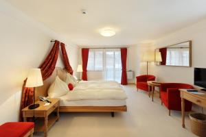 a bedroom with a bed and a desk and red chairs at Hotel Bellerive Gstaad in Gstaad