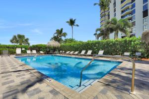a swimming pool with lounge chairs and a building at Somerset three-bedroom end unit beachfront condo in Marco Island