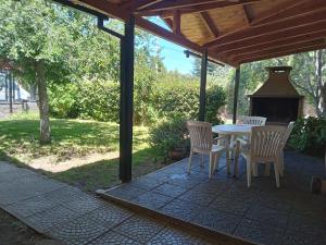 a patio with a table and chairs and a fireplace at Cabaña con costa al Lago Nahuel Huapi in San Carlos de Bariloche