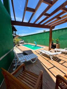 a deck with chairs and a swimming pool at Oásis Pousada in Bertioga