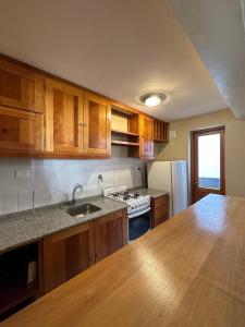 Una cocina con gabinetes de madera y encimera. en Casita Roca - Pleno Centro, en San Martín de los Andes 7 fotos más