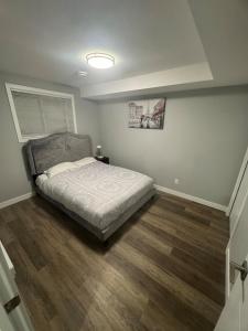 a bedroom with a bed and a wooden floor at 2-Bedrooms - On site Parking - near YQR Airport in Regina