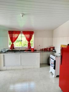 a kitchen with a counter and a window with red curtains at Casinha Virtuosa in Monte Sião
