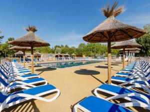 eine Reihe von blauen und weißen Stühlen und Sonnenschirmen am Pool in der Unterkunft Domaine Résidentiel de Plein Air Les Demoiselles in Saint-Hilaire-de-Riez