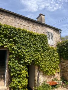an ivy covered brick building with a door at La Petite Ecluse in Tanlay