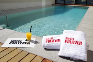 a hotel provider towels and a drink next to a swimming pool at Hotel Pulitzer Buenos Aires in Buenos Aires