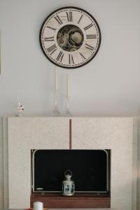 un reloj en la pared sobre una TV en Meli-Anas House, en Nea Iraklitsa