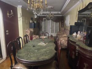 una sala da pranzo con tavolo, sedie e lampadario di loran flat a Il Cairo
