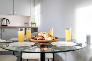 a glass table with a plate of food and orange juice at 3 BDR House in Kingston upon Thames, London Waterloo in 30 mins in Kingston upon Thames +35 photos