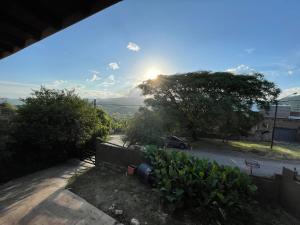 Blick auf eine Straße mit einem Baum und der Sonne in der Unterkunft Casa con pileta - Rio Ceballos - a 5 min del centro - Hermosa vista a las sierras in Río Ceballos