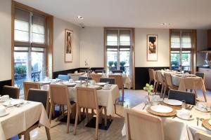 Un restaurante con mesas y sillas blancas y ventanas. en Marceau Champs-Elysées, en París 24 fotos más