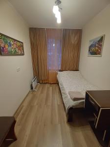 a bedroom with a bed and a desk and a window at Cozy rooms near beautiful Park 1st Floor in Chişinău