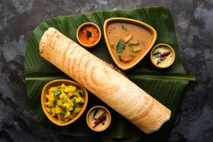 a plate of food with a burrito and soup on a banana leaf at Park Inn by Radisson Ayodhya in Ayodhya