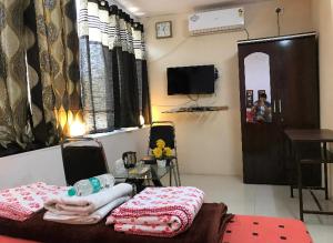 a room with a bed and a table and a television at Mutha's Homestay in Aurangabad