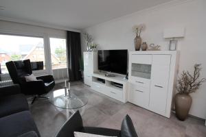 a living room with a white entertainment center with a television at Haus Norderhoog Wohnung 31 in Westerland (Sylt)