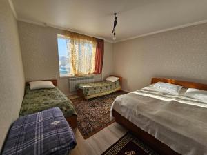 a hotel room with two beds and a window at Guesthouse Alinazar in Karakol