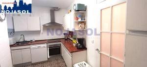 a small kitchen with white cabinets and a sink at Apartamento las Huertas in Santoña +8 photos