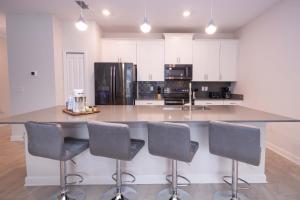 a kitchen with a large island with four bar chairs at 2901 SS Discover Opulence 4-Bedroom Villa with Pool, and Magical Themed Rooms! in Kissimmee