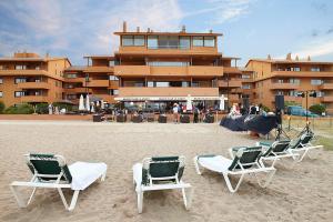 a group of lawn chairs sitting on the beach at Apartaments Beach & Golf Resort in Pals
