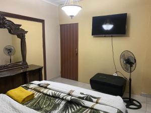 a bedroom with a bed with a fan and a television at Savannah Guest House Mafikeng in Mahikeng