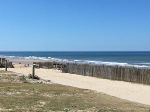 una spiaggia sabbiosa con recinzione e oceano di Les Pieds dans l'Eau a Lacanau-Océan