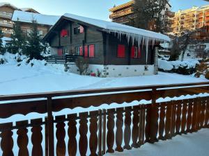 a house with a fence in the snow at New studio in Crans center in Crans-Montana