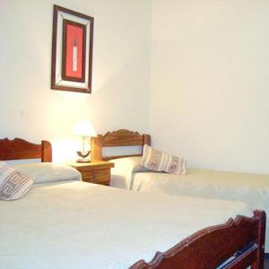 a bedroom with two beds and a table with a lamp at Hotel Wilton in Mar del Plata +5 photos