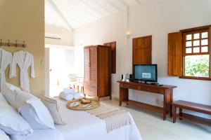 a bedroom with a bed with a television and a desk at Divina Pousada in Pirenópolis