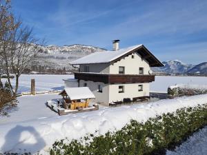 a house covered in snow in front of a lake at Haus Milan in Sankt Johann in Tirol