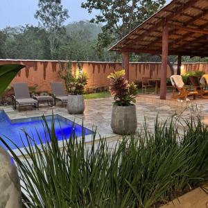 a patio with a pool and chairs and a pavilion at Pousada Renascer Park in Pirenópolis +94 photos