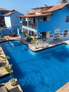 a large swimming pool in front of a blue house at Pousada Granada in Rio das Ostras