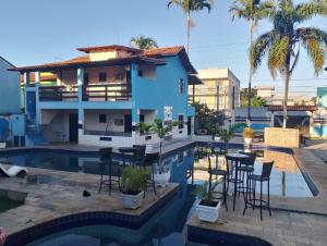 a villa with a swimming pool and a house at Pousada Granada in Rio das Ostras