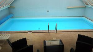 a large swimming pool in a room with chairs and a table at Logis Hôtel & Restaurant du Sauvage in La Ferté-Gaucher