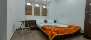 1 dormitorio con 1 cama con mesa y 2 ventanas en Laxmi Vilas, en Sām