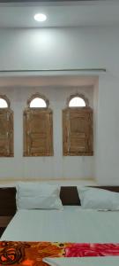 Un dormitorio con dos ventanas y una cama con sábanas blancas. en Laxmi Vilas, en Sām