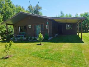 una pequeña casa con un patio de hierba delante de ella en Cabaña Canto del Zorzal, en Villarrica